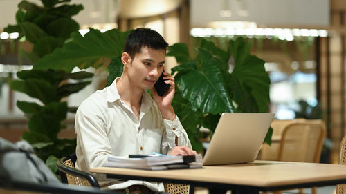 Young woman using mobile phone while sitting in cafe