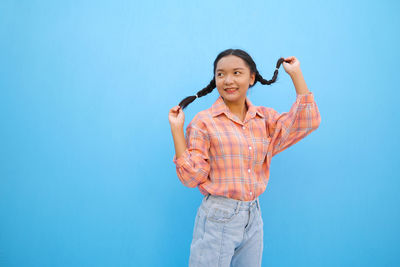 Portrait of smiling young woman standing against blue sky