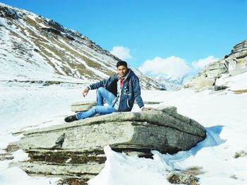 Full length of young man standing on rock in snow