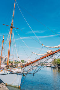 Sailboat moored on river against blue sky