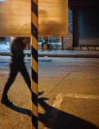 Shadow of person walking on footpath in city