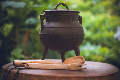 Close-up of wooden spoon and carving fork by container on wood