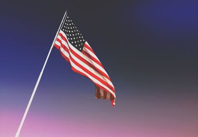 Low angle view of american flag waving against sky during sunset