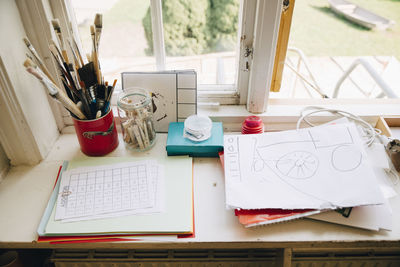 High angle view of papers and paintbrushes on window sill in classroom