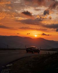 Car on road against mountain and sky during sunset