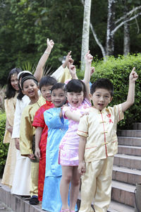 Cute friends with hand raised in traditional clothing standing on steps