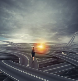 Man standing on railing against sky during sunset