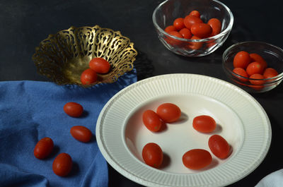 Cherry tomatoes on a table and in bowls and plate