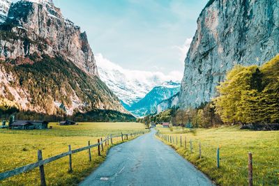 Road amidst green landscape and mountains against sky