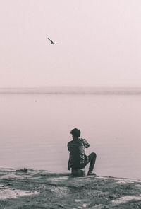 Man flying over sea against sky