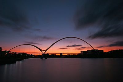 Bridge over river against sky at dusk