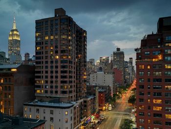 Illuminated buildings in city against sky at dusk