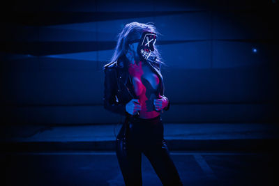 Woman standing against illuminated wall at night