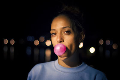 Close-up portrait of woman blowing bubble gum