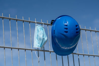 Low angle view of metal fence against blue sky