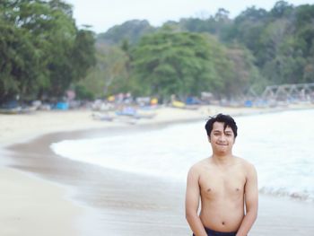 Portrait of shirtless man standing on beach