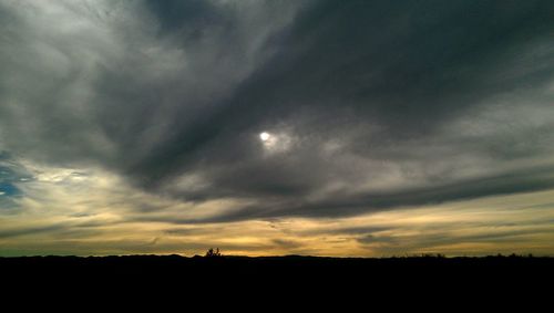 Silhouette of landscape against cloudy sky