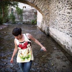 Woman walking in river by stone wall