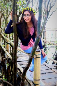 Portrait of young woman standing against trees