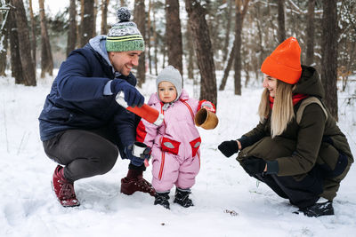 Outdoor family activities for happy winter holidays. happy father and mother playing with little