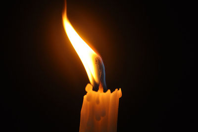 Close-up of lit candle against black background