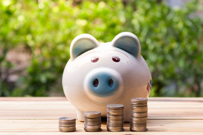 Stacks of coins and piggy bank on table