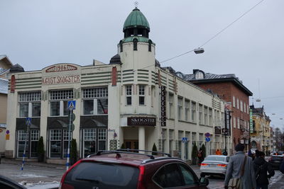 Cars on city street against sky