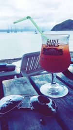 Close-up of wine glasses on table at beach