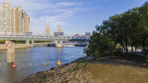 Bridge over river in city against sky