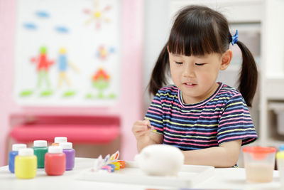 Cute baby girl sitting on table at home