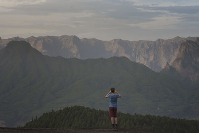 Rear view of man standing against mountain