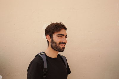 Portrait of smiling young man standing against wall