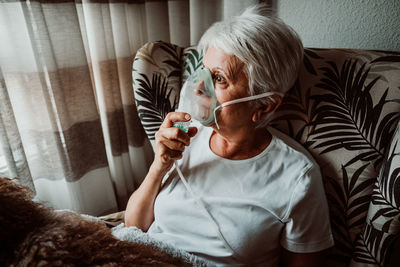 Midsection of woman sitting on sofa at home