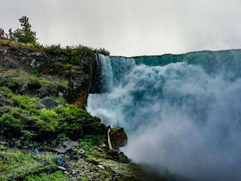 Scenic view of waterfall in forest against sky