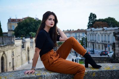 Portrait of young woman sitting in city