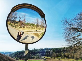 Reflection of trees on mirror against sky