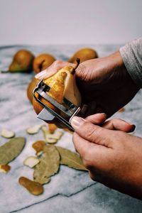 Cropped image of person peeling pear on table