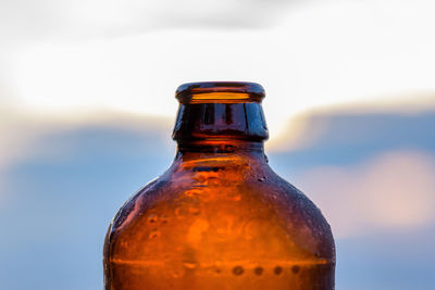 Close-up of water drops on beer bottle against evening sky