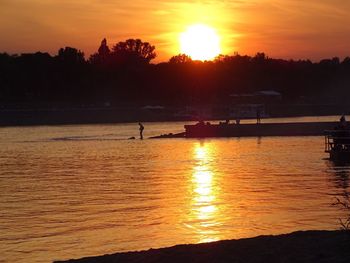 Silhouette man by sea against sky during sunset