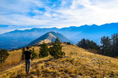 Rear view of man standing on mountain against sky