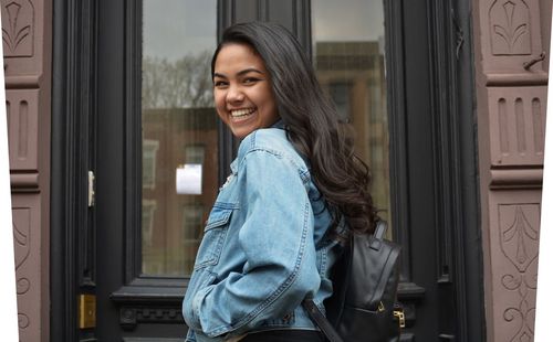 Portrait of young woman standing against window