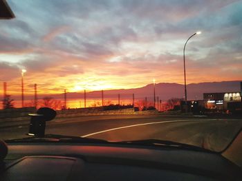 Cars on street against sky during sunset