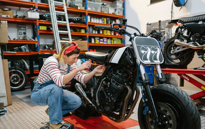 Mechanic woman repairing custom motorcycle on factory