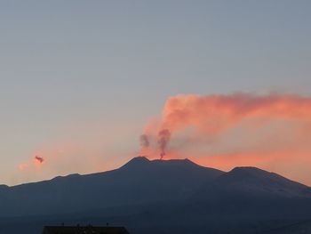 Smoke emitting from mountain against sky