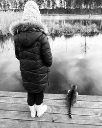 Rear view of woman standing on pier over lake