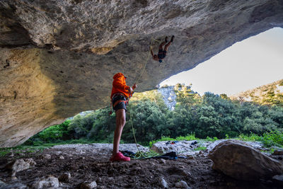 Man with friend balancing on rope in cave