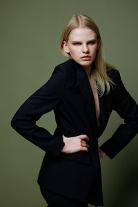 Portrait of young woman standing against wall