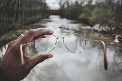 Close-up of hand holding leaf against sky