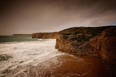 Rock formations on beach against sky