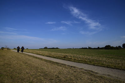 People walking on field against sky